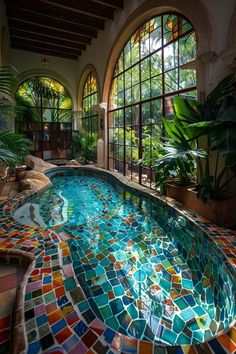 an indoor swimming pool with colorful tiles on the bottom and sides, surrounded by large windows