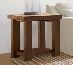 a wooden table with a glass jar on it next to a white couch in a living room