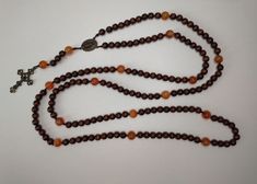 "Handmade 15 decade rosary in beautiful 7mm wood beads and 10mm calcite beads. This beautiful peace evokes the humility and simplicity of Franciscan monks, while the blazing orange calcite was inspired by the tongues of fire that descended on Christ's disciples.  Strung together with 1mm nylon cord, the rosary should withstand up to 10kg of pressure, making it not as delicate as it looks.  Measures 80cm / 31.5\"  Handmade in France Chapelet de 15 dizaines fait à la main en belles perles de bois Brown Rosary Bracelet With 8mm Beads For Meditation, Spiritual Brown Rosary For Healing, Amber Rosary With 8mm Beads In Spiritual Style, Amber Rosary With 8mm Beads, Spiritual Style, Amber Rosary With 8mm Beads, Spiritual Amber Rosary With 8mm Beads, Brown Beaded Spiritual Rosary, Amber 8mm Beads Spiritual Rosary, Brown Healing Rosary With Round Beads