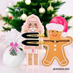 two wooden cutouts with christmas decorations and a tree in the background, one is holding a paintbrush