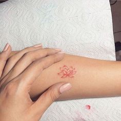 two hands holding each other with a small tattoo on their arm and wrist, both showing red ink