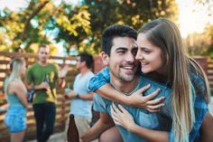 a man is hugging a woman in front of other people at a park with beer bottles