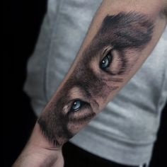 a man's arm with a wolf tattoo on it and an eye in the middle