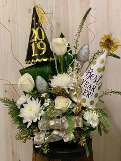 a vase filled with flowers and a party hat on top of a wooden table next to a wall