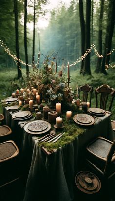 a table set with candles, plates and place settings in the woods for an outdoor dinner