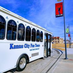 the bus is parked on the side of the road next to the street sign that says kansas city fun tour