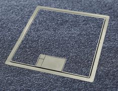 a square metal object sitting on top of a blue carpeted floor next to a window