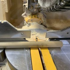 a machine that is cutting something yellow on it's side and some metal bars in front of it