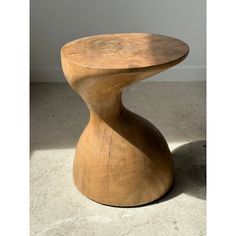 a wooden stool sitting on top of a cement floor next to a wall and window