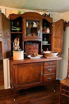 an old fashioned kitchen with wooden cabinets and wood flooring, including a table that has utensils on it