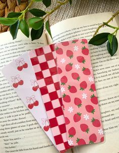 three bookmarks with strawberries and checkered paper on top of an open book