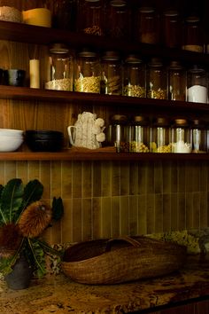 the shelves are filled with jars, bowls and other items on display in this kitchen