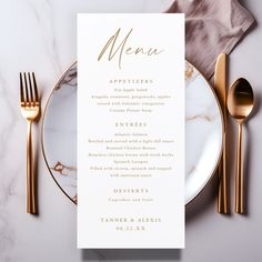 a table setting with gold cutlery and white menu cards on it, along with silverware