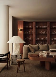 a living room filled with furniture next to a tall wooden shelf covered in glass bottles