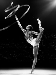 a black and white photo of a woman doing a trick with ribbon in the air