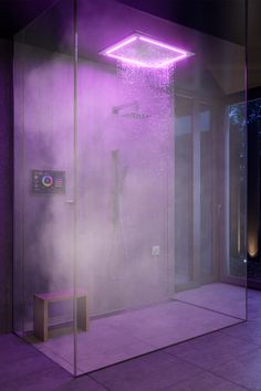 a shower with steam coming out of it and purple lighting on the wall behind it