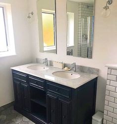 a bathroom with double sinks and two mirrors