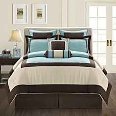 a bed with teal and brown comforters in a room next to a table