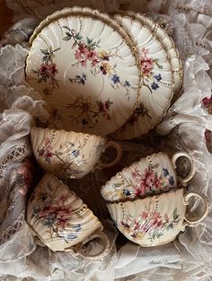 an assortment of porcelain dishes and cups on lace