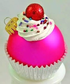 a cupcake ornament on top of a pink ball