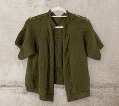 a green cardigan sweater hanging on a white wall