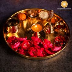 a brass tray with candles and flowers on the bottom, surrounded by other items that are in it