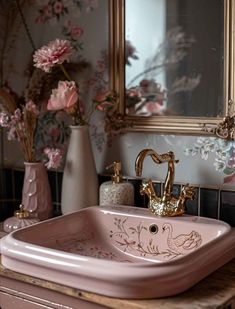 a pink sink sitting on top of a wooden counter next to a vase filled with flowers