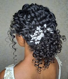 the back of a woman's head with curly hair and flowers in her hair