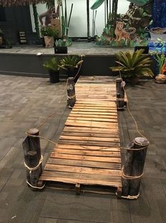 a wooden walkway made out of logs and roped off with plants in the background