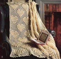 a chair with a blanket on top of it and a book in front of the chair