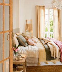 a bed with pillows and blankets on top of it in a bedroom next to a window