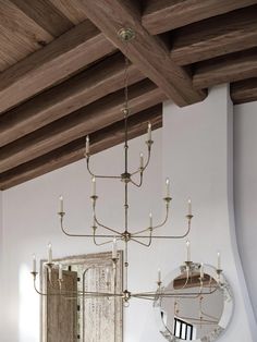 a chandelier hanging from the ceiling in a room with white walls and wood beams