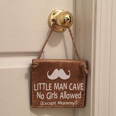 a little man cave sign hanging on the front door to someone's house with a moustache