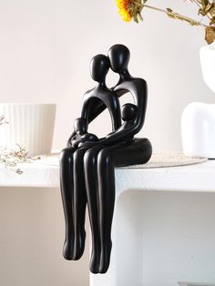 a black sculpture sitting on top of a table next to a vase filled with flowers