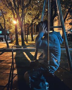 a person sitting on the ground with their head in his hands, next to a swing set