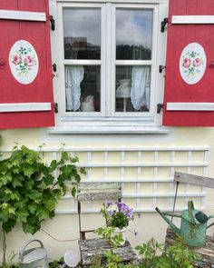 an old wooden bench sitting in front of a window with red shutters and flowers