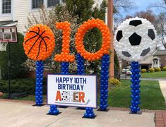 two balloons that say happy 10th birthday and one with a soccer ball on it are in front of a house