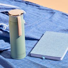 a book and a water bottle sitting on a blue blanket next to a metal flask