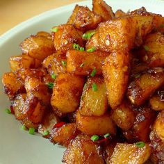 a white plate topped with fried potatoes on top of a wooden table