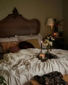 an unmade bed with candles and flowers on it