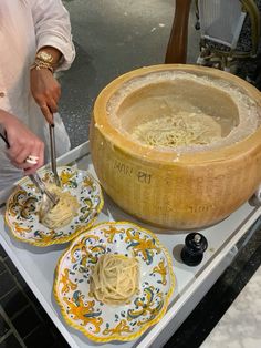 a woman is making pasta in a wooden pot on a stove top with two plates