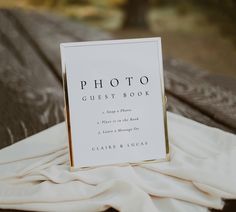 a photo guest book sitting on top of a wooden table next to a white cloth