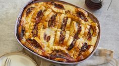 a casserole dish with meat and cheese in it on a table next to a plate