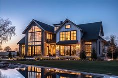 a large house with lots of windows next to a body of water at night time