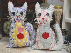 two stuffed cats sitting next to each other on top of a table covered in papers