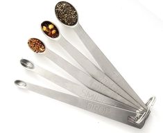 five measuring spoons with different types of spices in them