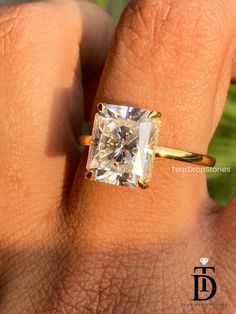 a woman's hand with a yellow gold ring and a white diamond in it