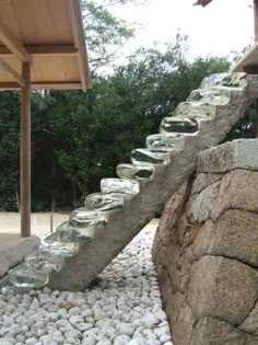 a stone wall with glass bowls on it and some trees in the backround