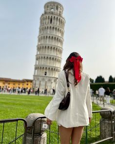 a woman is standing in front of the leaning tower