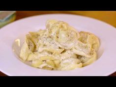 a white plate topped with pasta covered in gravy on top of a wooden table